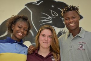 Mental Health 1 Three students smiling in front of a large panther logo