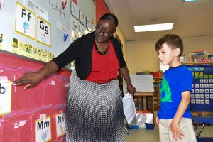 TEACH 1 Teacher shows letter cards to a young student in a classroom