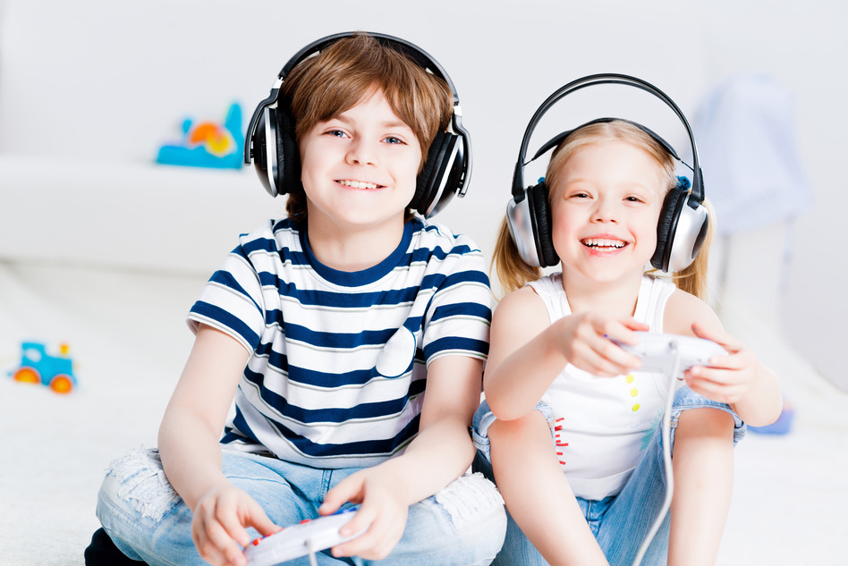 Safe Gaming Two smiling kids wearing headphones play video games.